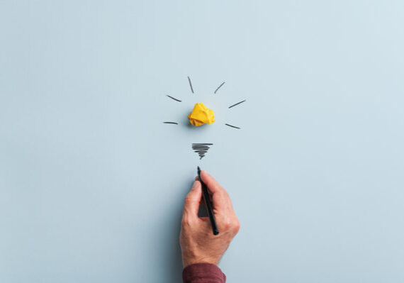 Male hand drawing a light bulb over blue background in a conceptual image.